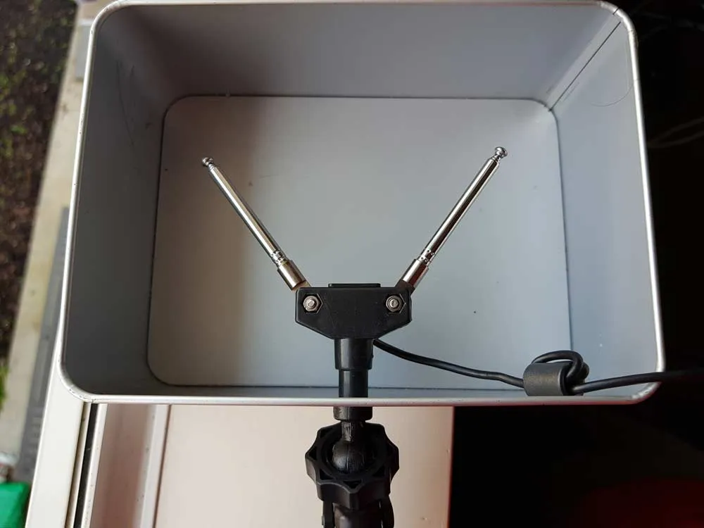 An RTL-SDR dipole opened into a V inside a metal reflector for an L-band satellite reception experiment.